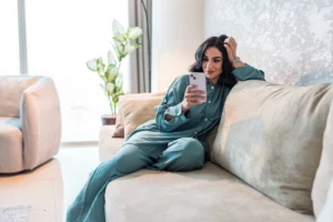 Personne consultant son téléphone depuis son domicile dans le cadre d’une consultation en phytothérapie à distance.